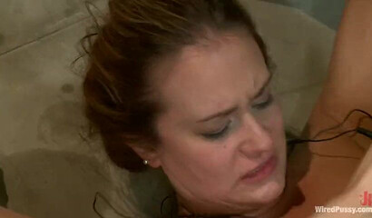 Big titted MILF tied up to a table gets pleasured by skinny dyke